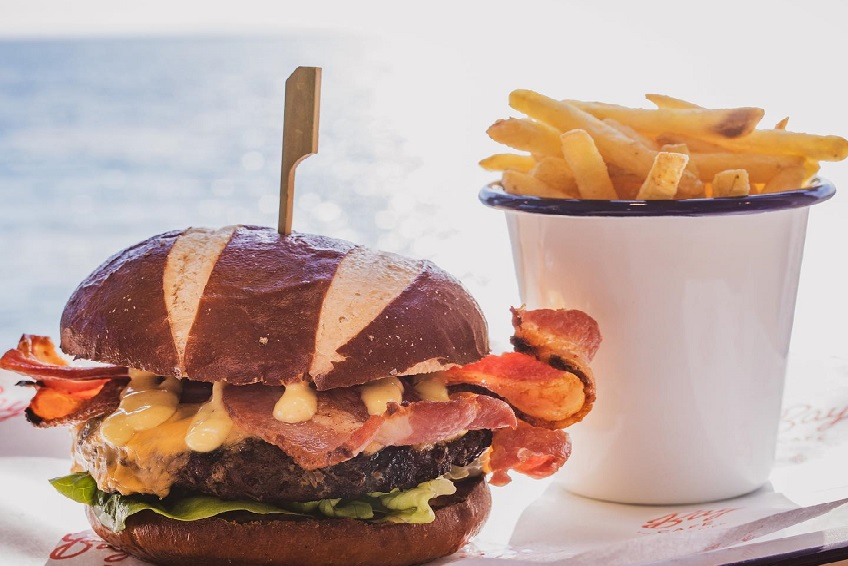 An artisanal bacon cheeseburger and bucket of crisps