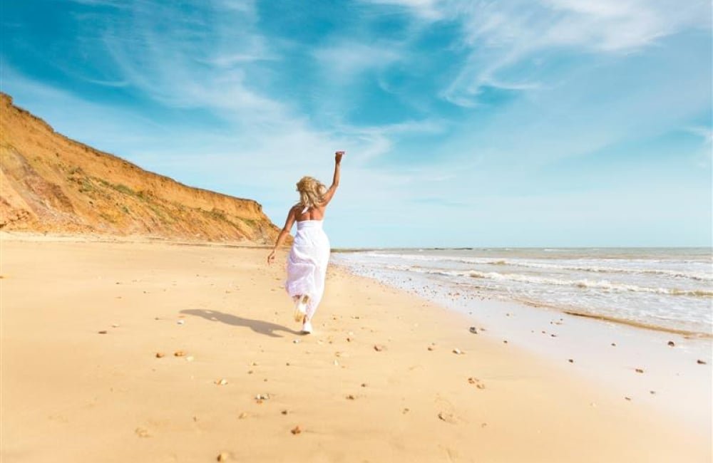 lady in a white dress running on the beach