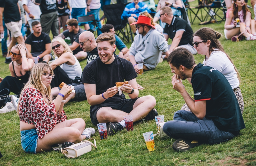 a group of people drinking cider and eating hot dogs