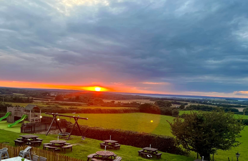 sunset over rolling country side, with picnic benches in the foreground