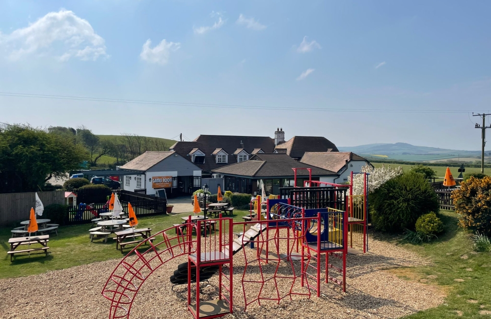 Children's playground with tables and chairs with countryside and blue skies in the background