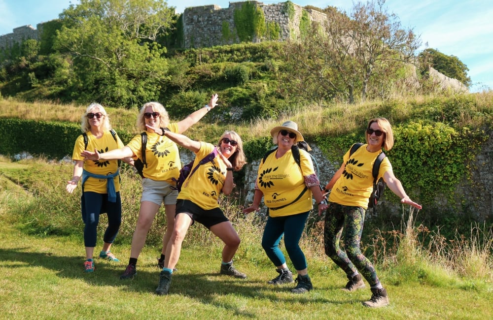 A group of walkers smiling and posing for a team photo with Carisbrooke castle in the background