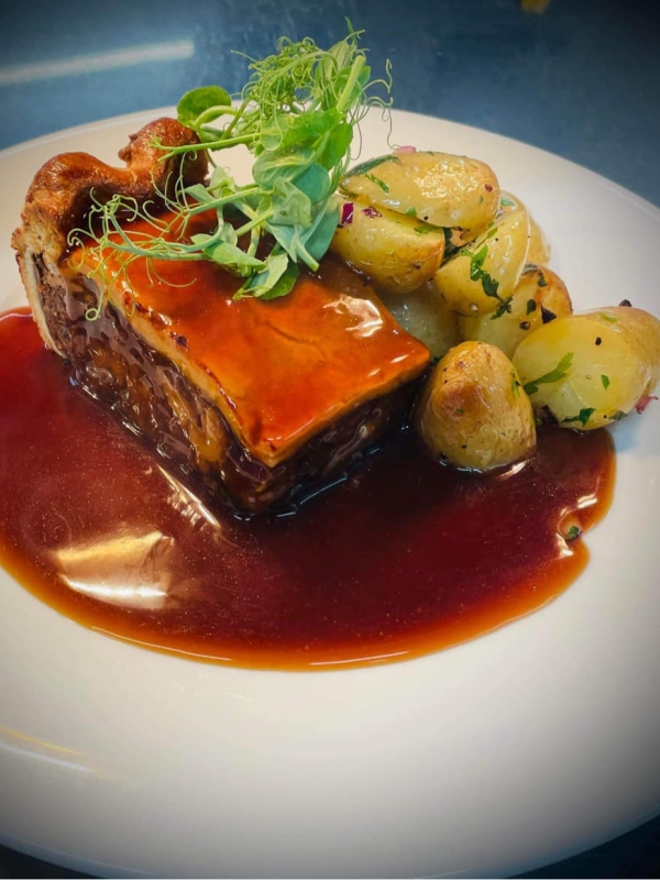 a plate with a slice of pie, potatoes and gravy