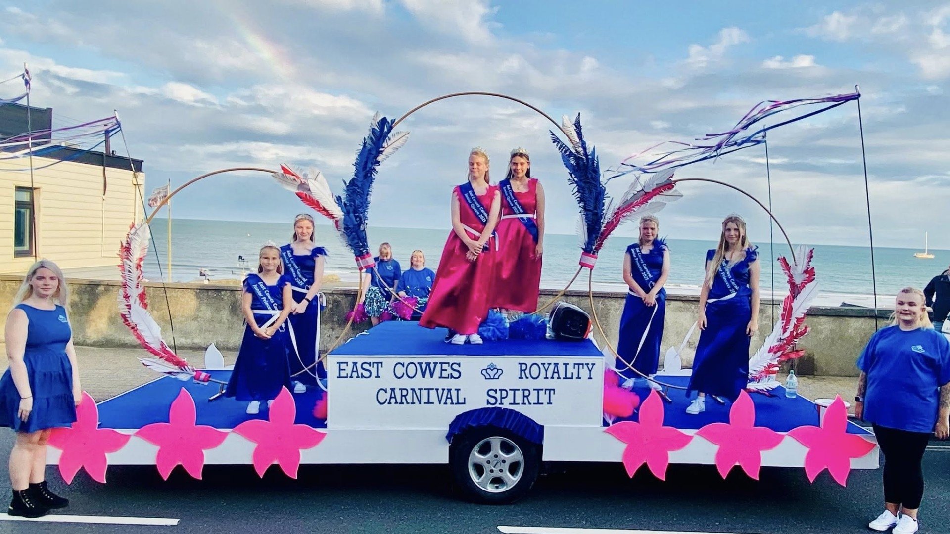 this year's carnival royalty, girls pose atop pink and blue decorated float