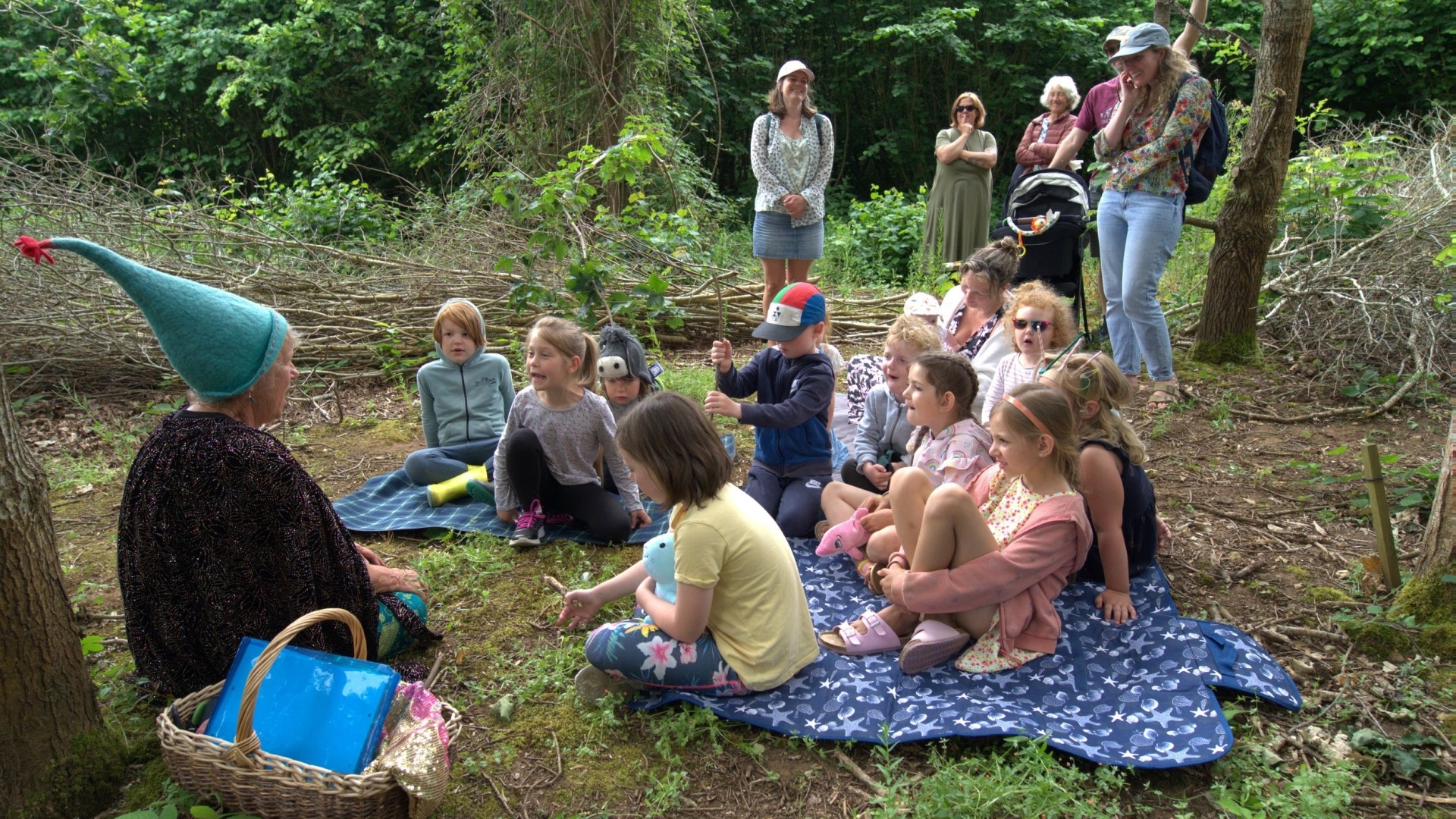 children sitting round for a story telling session in the woods