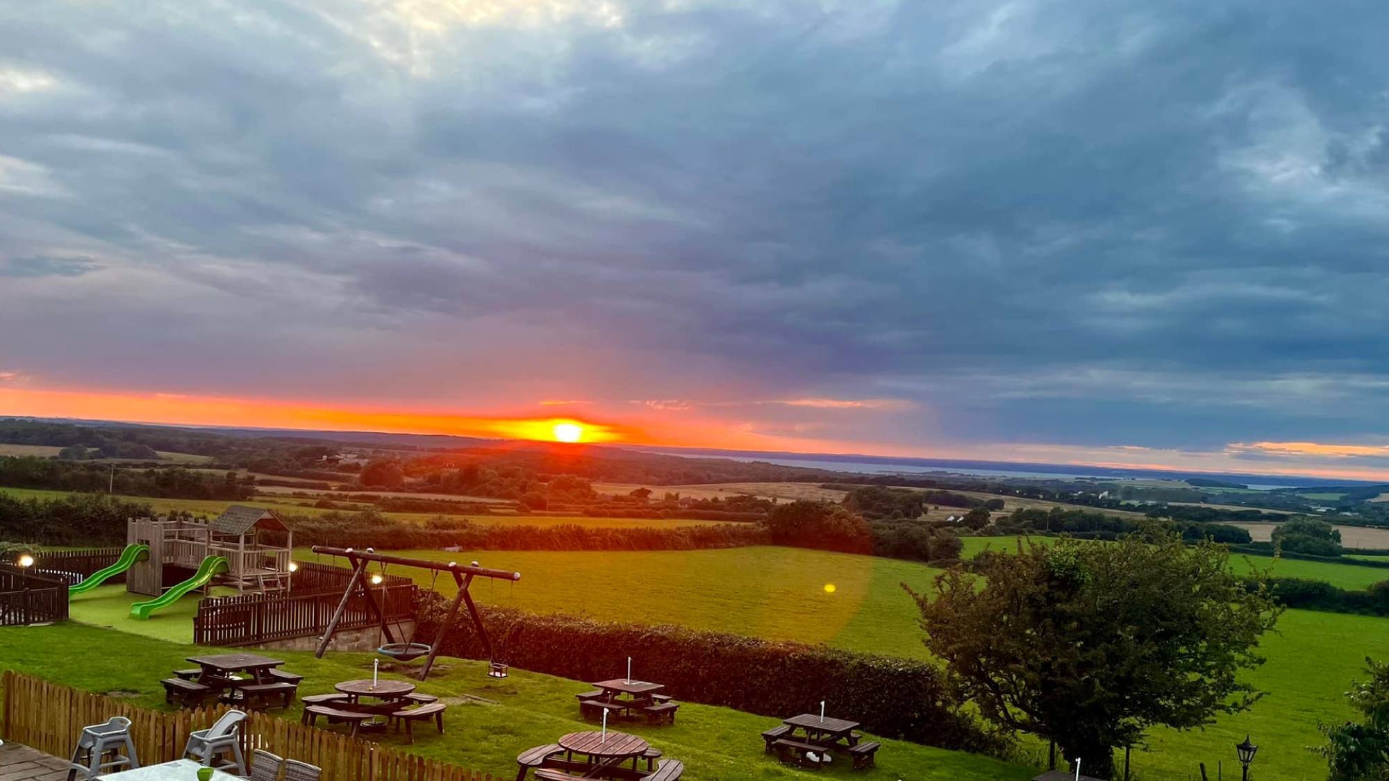 sunset over rolling country side, with picnic benches in the foreground