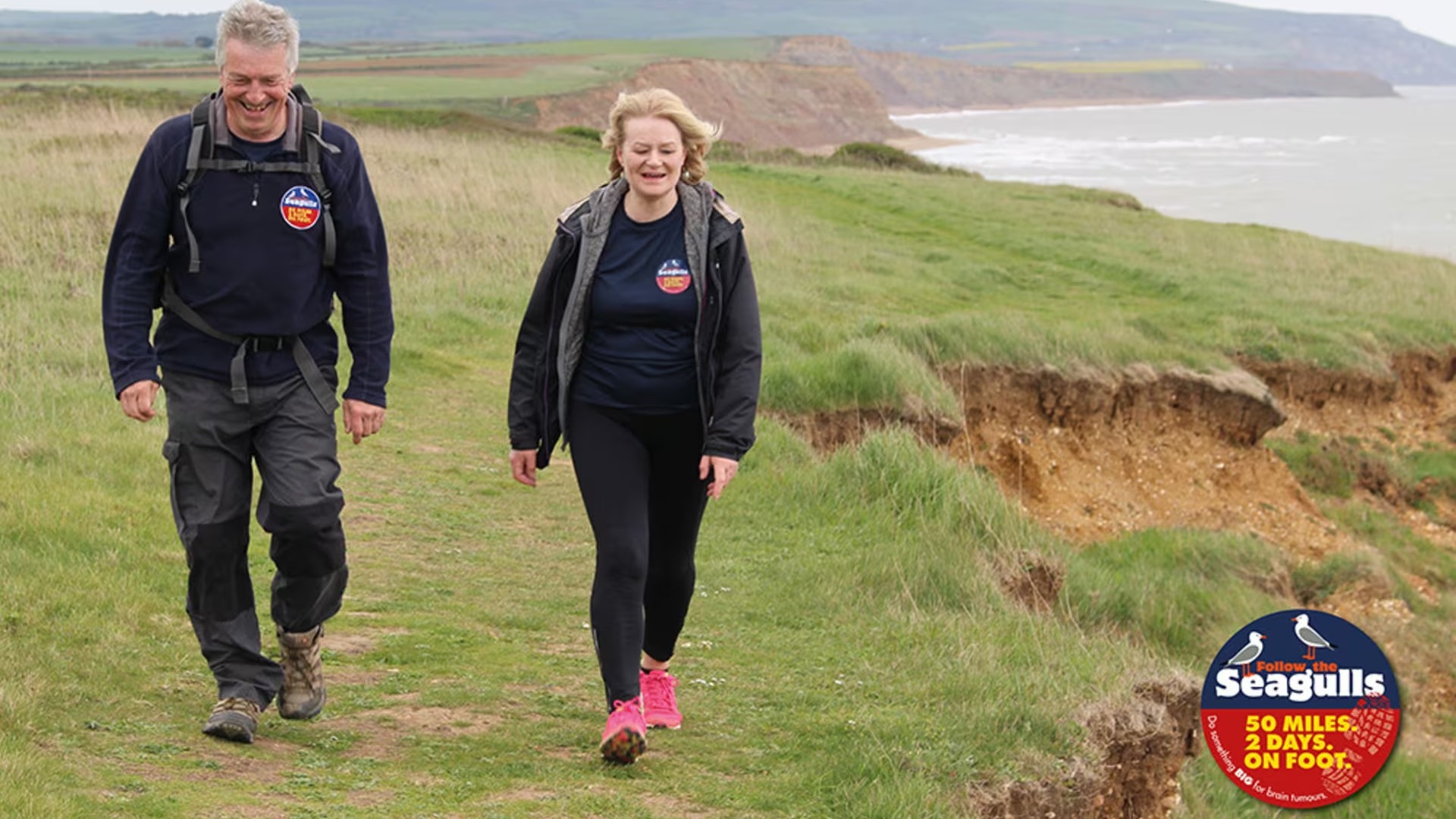 two hikers with clifftops and the sea in the background