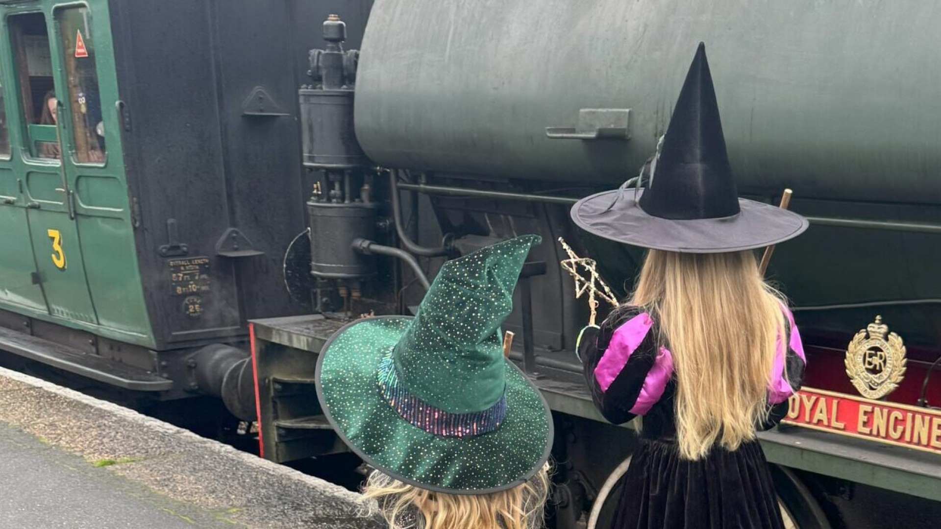 children in witch hat fancy dress next to train carriage