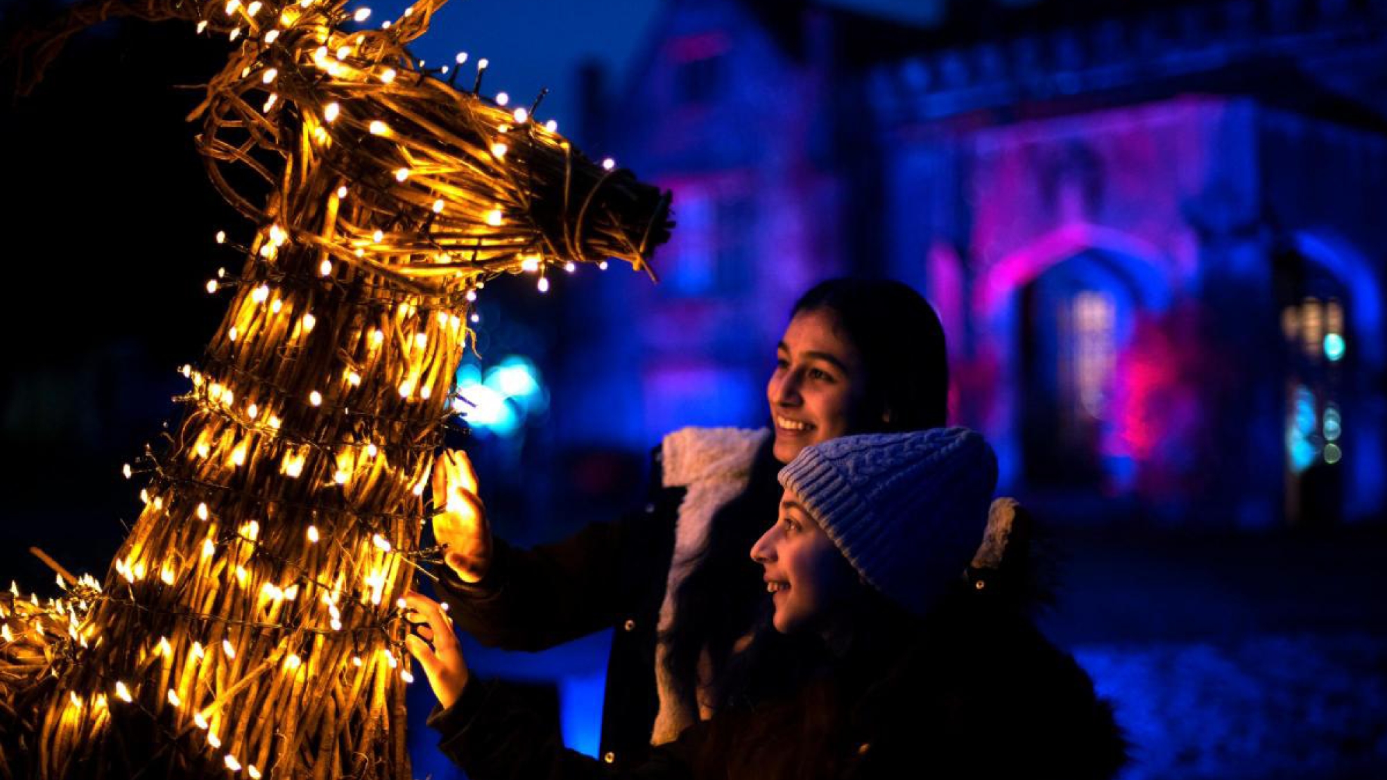 family looking at a reindeer model with fairy lights