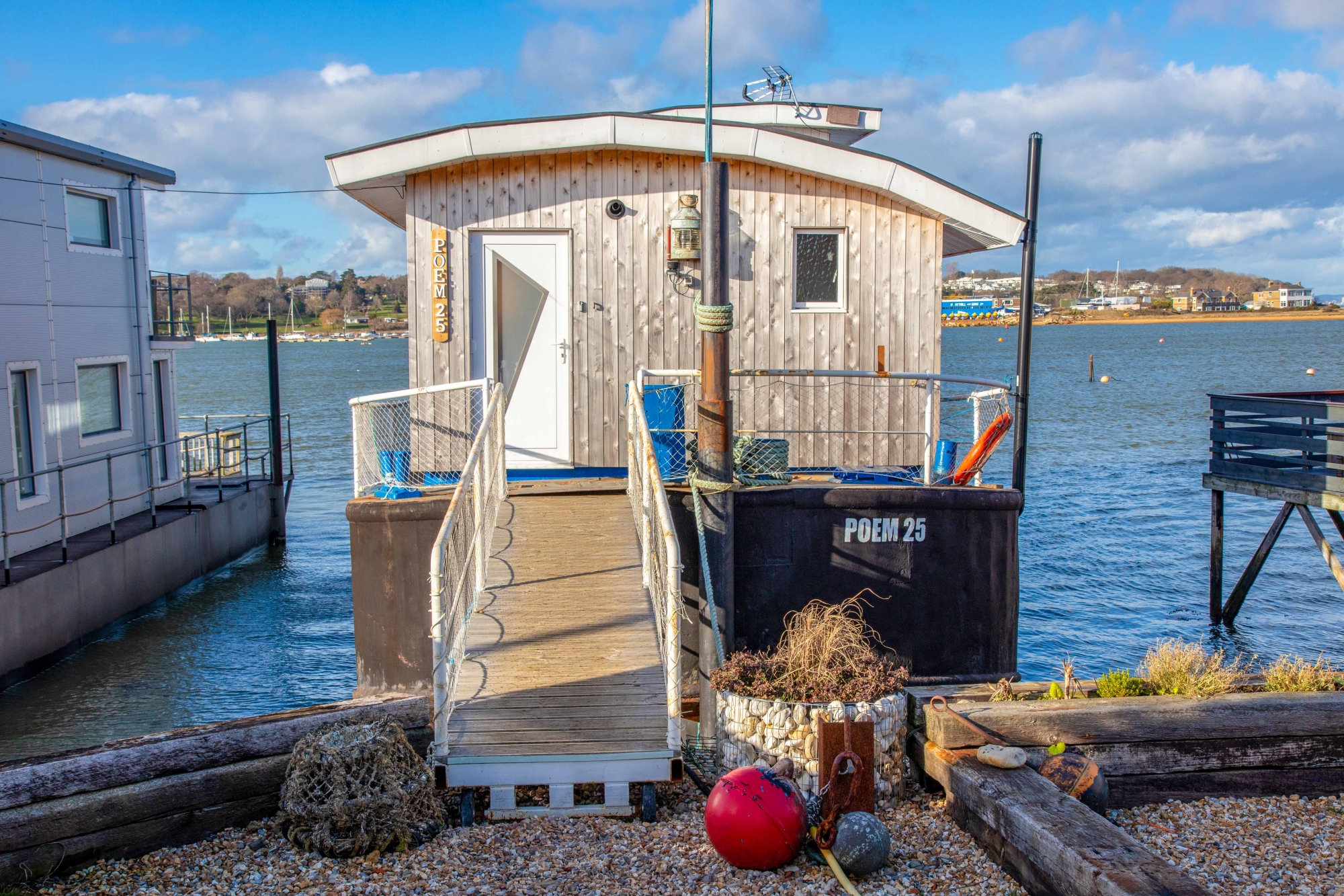House boat moored in harbour with ramp leading to front door