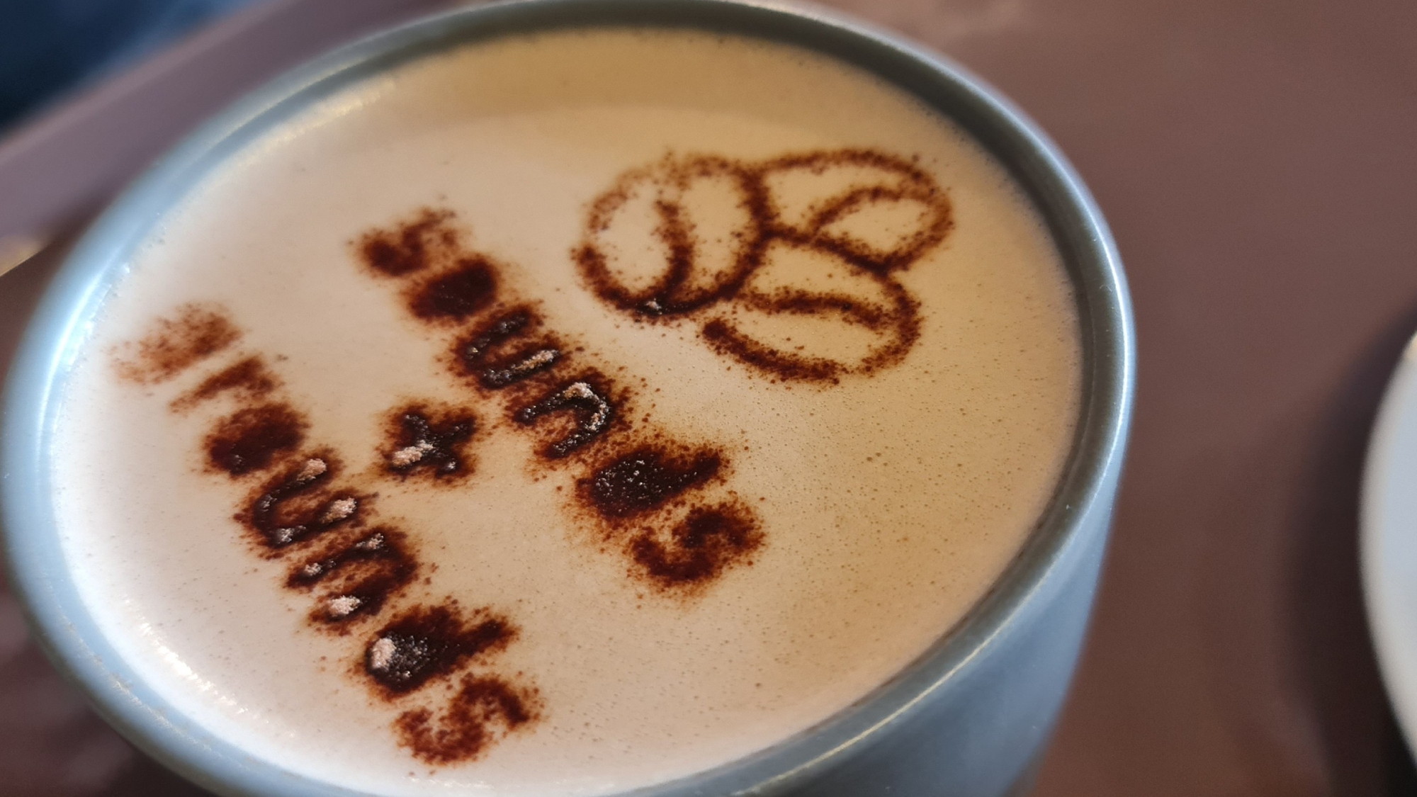 coffee cup with sounds and grounds sprinkled on top of foam