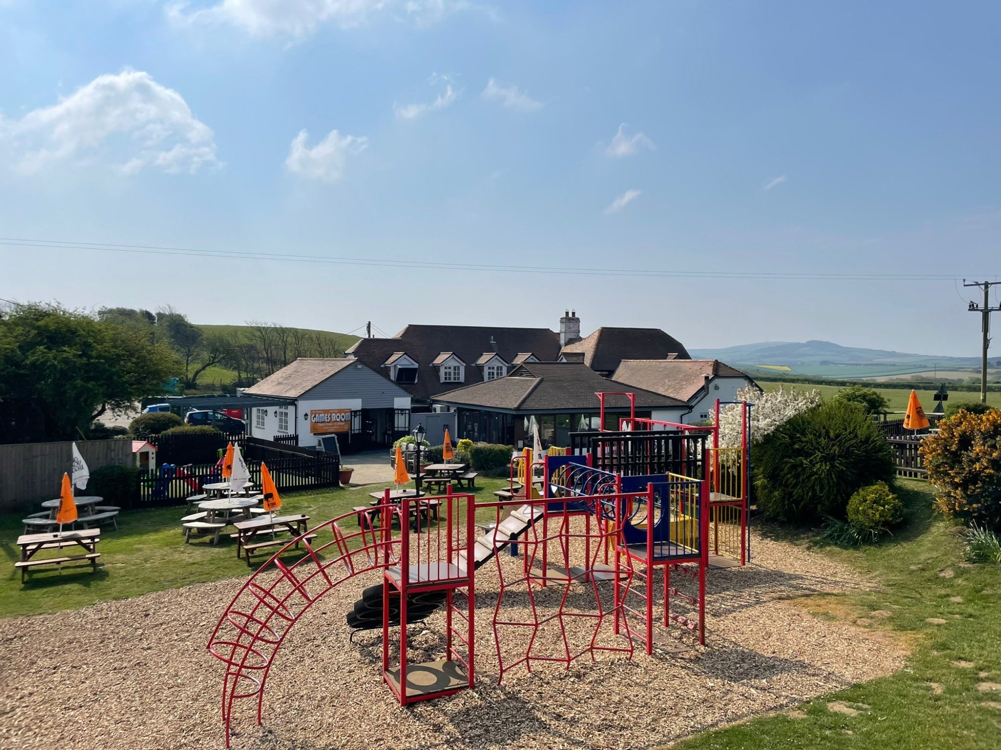 Children's playground with tables and chairs with countryside and blue skies in the background
