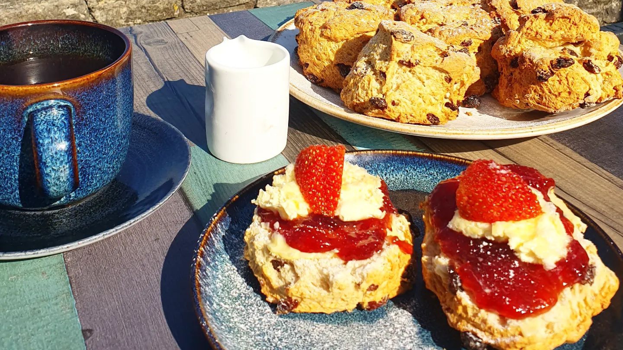 cream and jam scones and cup of coffee on a table