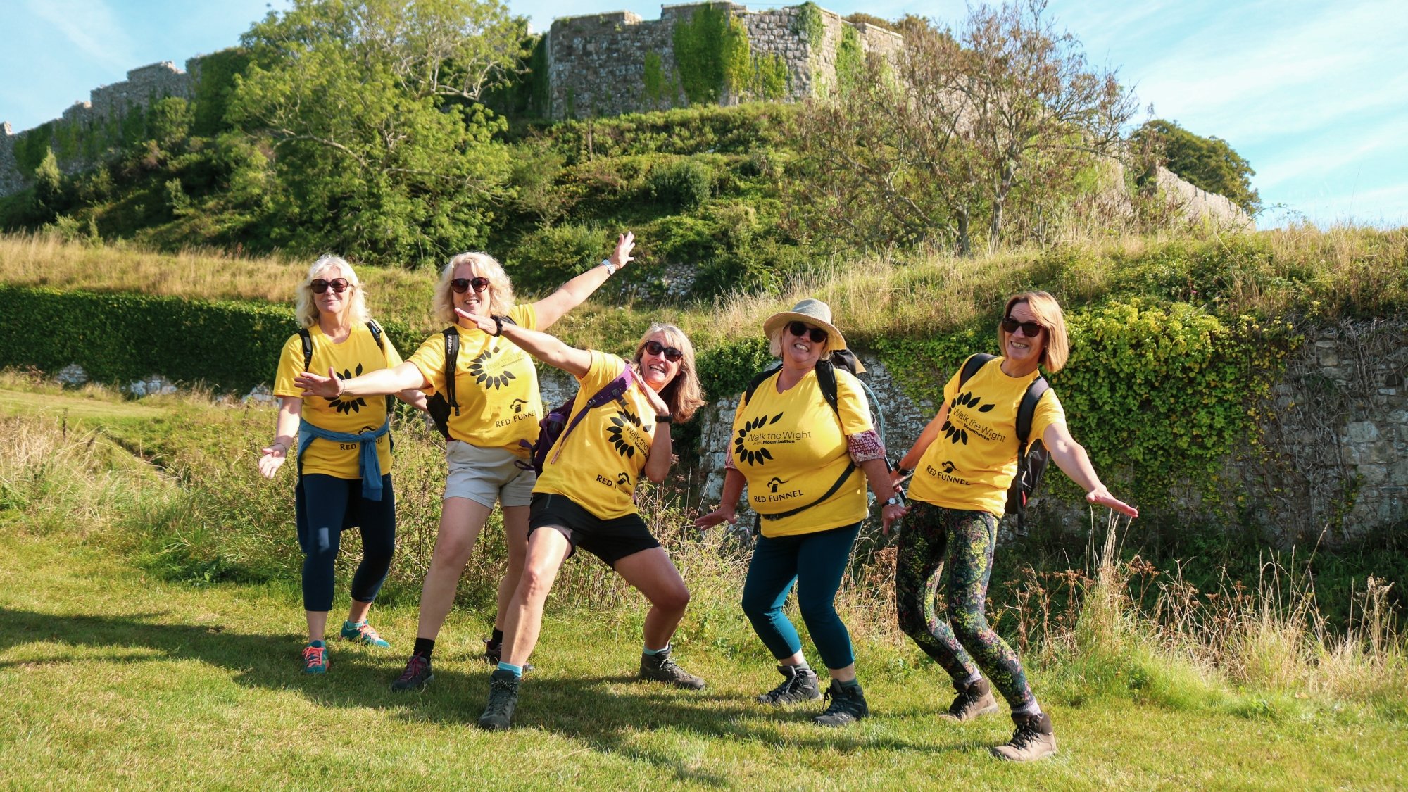 A group of walkers smiling and posing for a team photo with Carisbrooke castle in the background