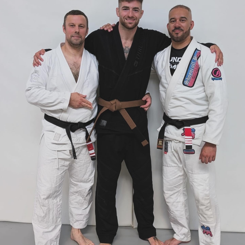 corey posing with his brown belt and his mentors