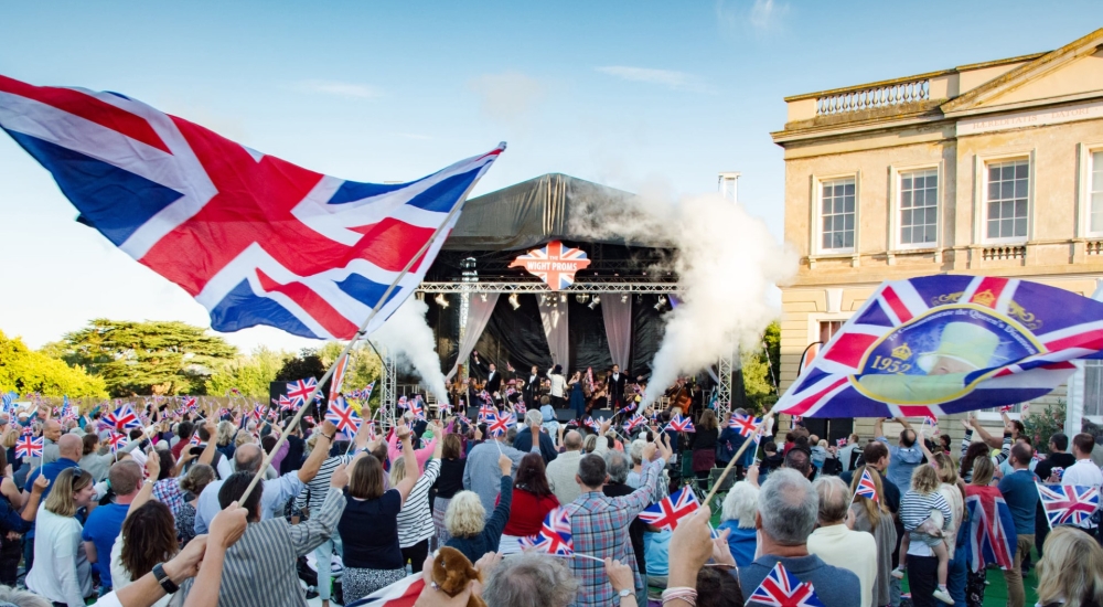 a crowd cheering and waving flags with the stage in the background