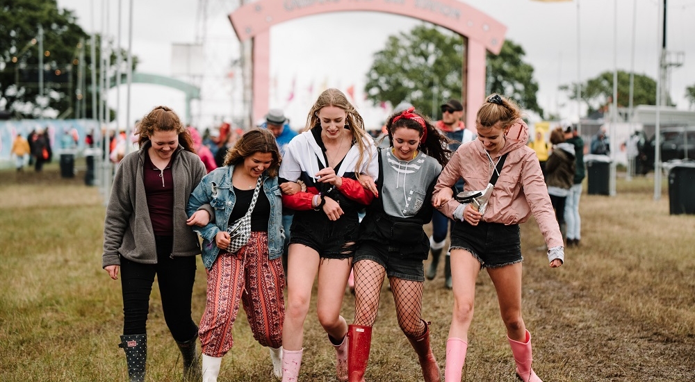 Group of ladies linked arms with festival arch in the background