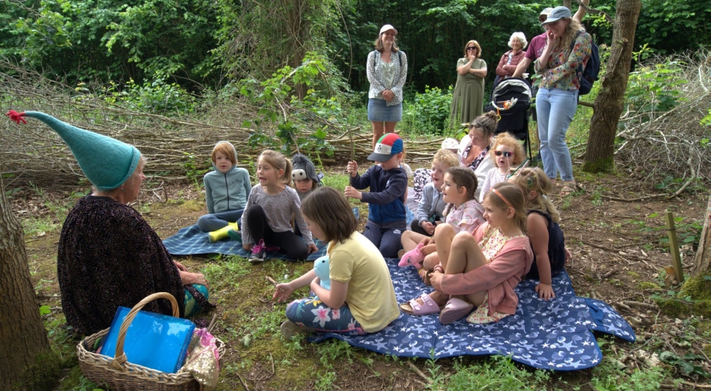 children sitting round for a story telling session in the woods