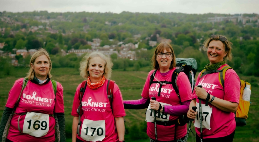 a group of smiling women in matching pink charity t shirts and walking gear