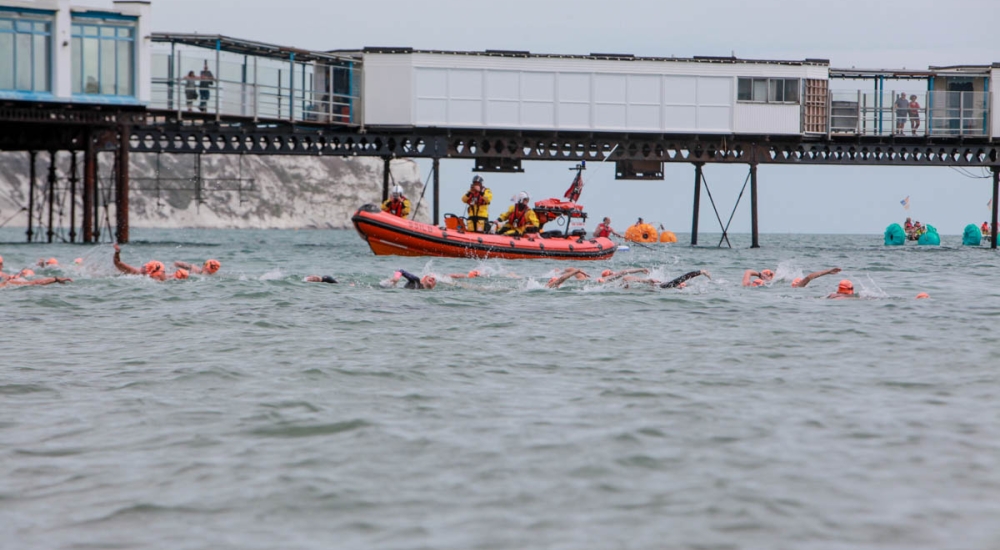 swimmers swimming past the pier