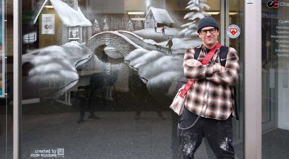 a snow window festive scene image with the artist posing in front